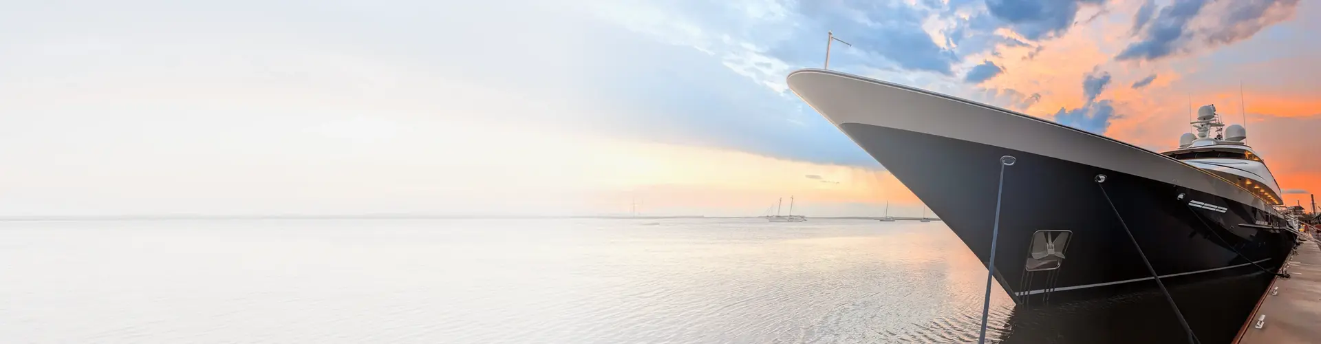 Luxury yacht docked at a marina during sunset